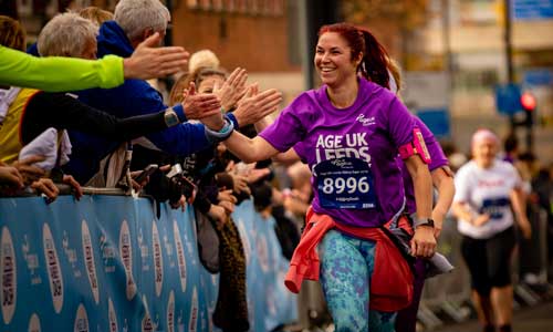 Woman giving high fives to the crowd whilst running in the 51¥Leeds Abbey Dash